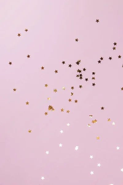 Golden star shaped confetti on pink pastel backdrop. — Stock Photo, Image