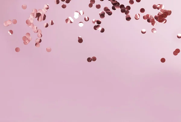 Brillante confeti de oro rosa sobre fondo de pastel rosa . — Foto de Stock