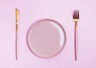 Pembe plaka, çatal ve bıçak pembe arka planda izole