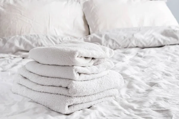 Toalhas brancas limpas na cama branca — Fotografia de Stock