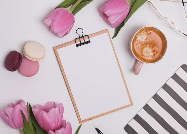 Feminin gestylter Arbeitsplatz mit Tulpen und Kaffee. — Stockfoto