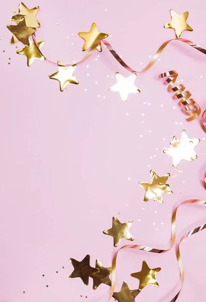 Golden decor star shaped confetti and ribbons isolated on pastel pink background — Stock Photo, Image