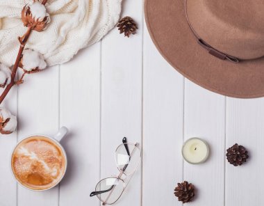 Şapka, kazak, kahve ve beyaz ahşap arka plan üzerinde diğer öğeler.