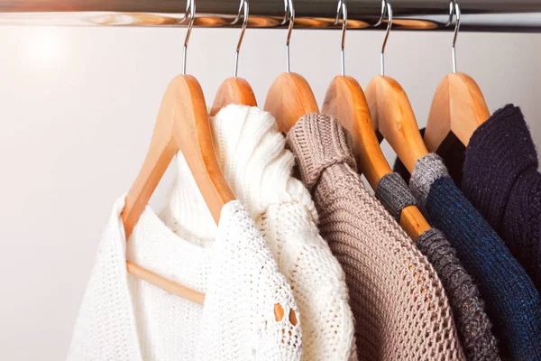 Strickpullover auf Kleiderbügeln an der weißen Wand Hintergrund — Stockfoto