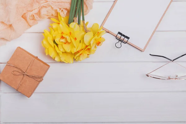 Jarní složení se žlutými květy, GiftBox a dalšími předměty na bílém dřevěném stole — Stock fotografie