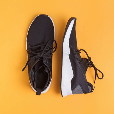 Parlak sarı arka planda koşmak veya fitness için siyah spor ayakkabılar,