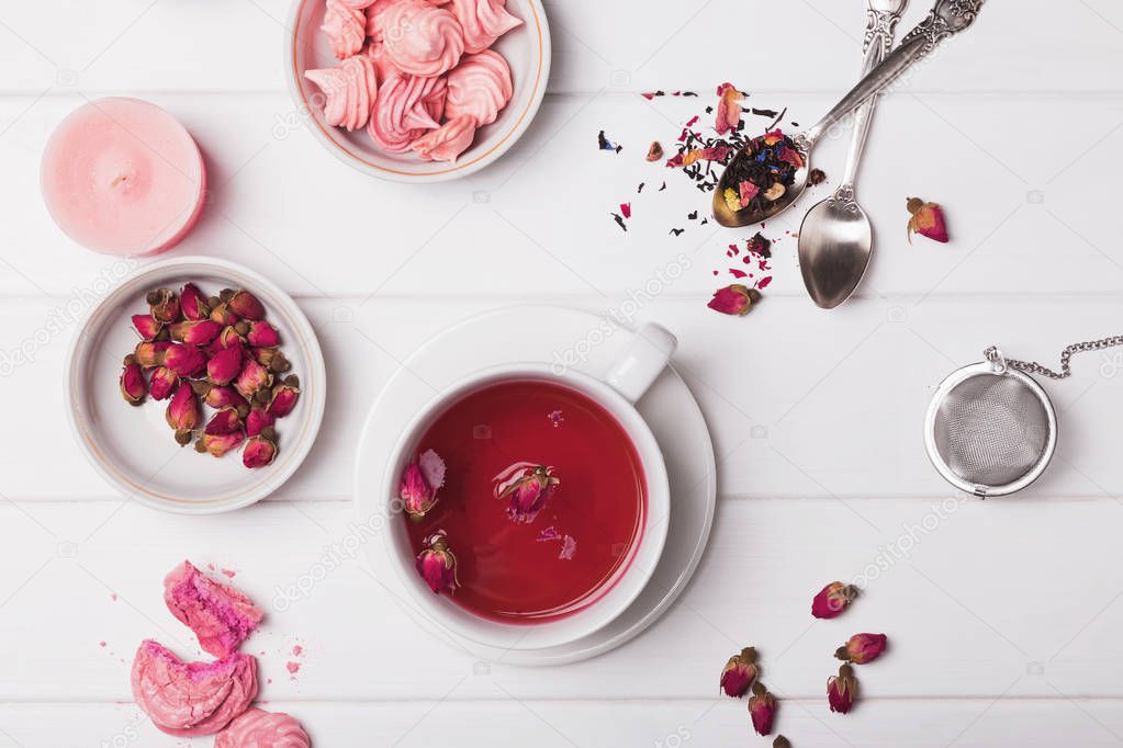 Floral tea in a cup, dried roses and other tea accessories on the white background