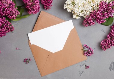 Lila çiçekleri ile gri arka plan üzerinde boş kağıt ile Zarf