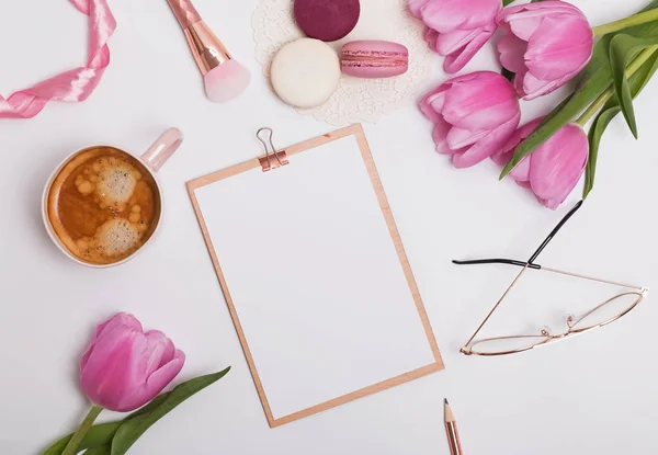 Feminine styled work place with tulips and coffee.