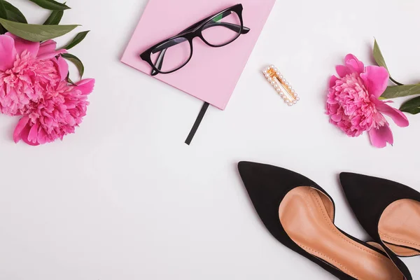 Vrouwelijke accessoires en mooie roze pioenrozen op de witte achtergrond — Stockfoto