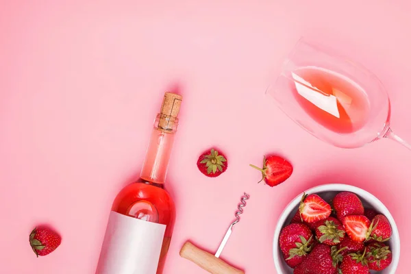 Pembe arka planda gül şarabı ve lezzetli çilek ile yaratıcı kompozisyon — Stok fotoğraf