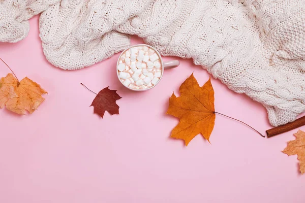 Höst komposition med stickad tröja, kakao med marshmallows och gula löv på rosa bakgrund — Stockfoto