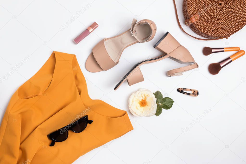 Feminine stylish summer outfit with sandals, straw hat and bag on the white table,