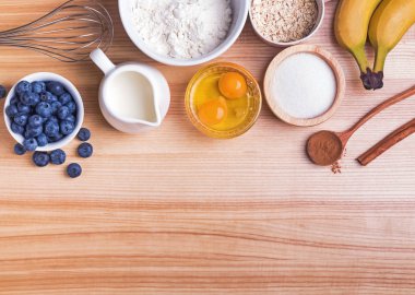 Ahşap masa üzerinde yaban mersini kekler hazırlık için Malzemeler, üst görünümü.