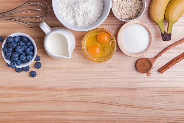 Ingredienser för blueberry muffins beredning på träbord, uppifrån. — Stockfoto