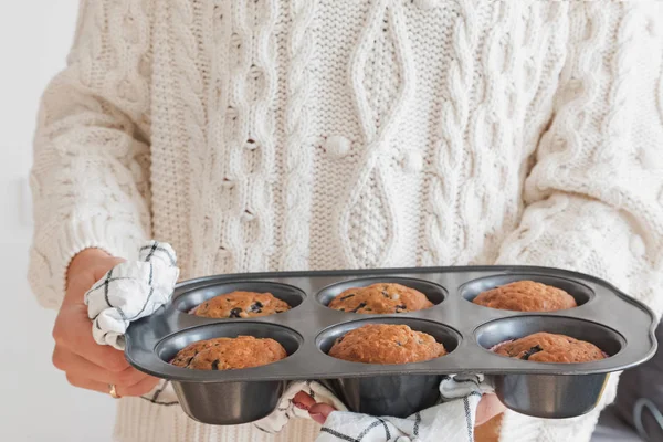 Womas mãos segurando uma bandeja com deliciosos muffins frescos assados — Fotografia de Stock