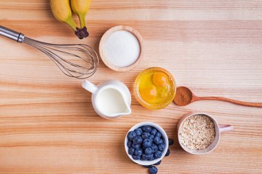 Ahşap masa üzerinde yaban mersini kekler hazırlık için Malzemeler, üst görünümü.