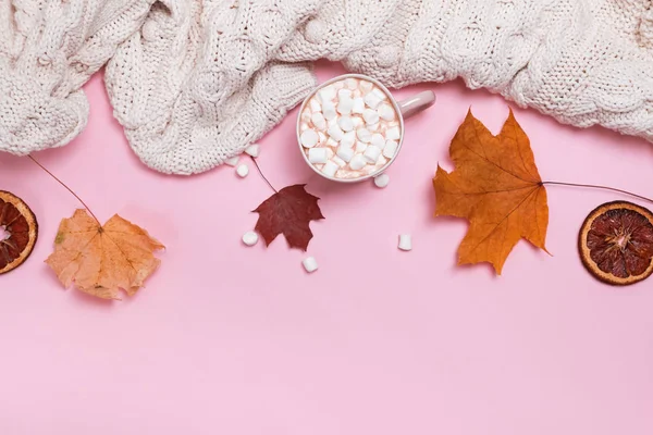 Őszi pulóver, kakaó, mályvacukrot és sárga levél rózsaszín háttérrel — Stock Fotó