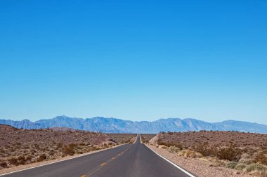 Dağlarla güneşli bir günde çölde boş asfalt yol