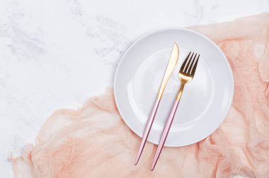 Beyaz mermer masada boş beyaz plaka ve modern tasarım çatal bıçak takımı