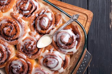 Krem peynir frosting ile sırlı bir fırın tepsisinde Lezzetli tarçın çörekler