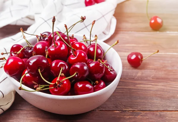 Köstliche reife Kirschen in einer Schüssel auf dem Holztisch — Stockfoto