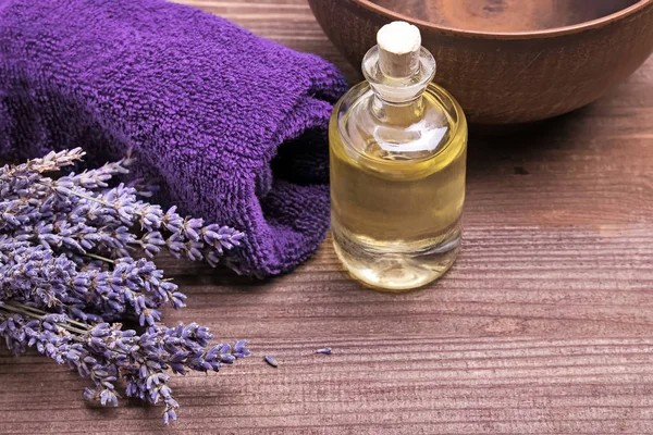 Massage olie fles en lavendel bloemen op houten achtergrond — Stockfoto