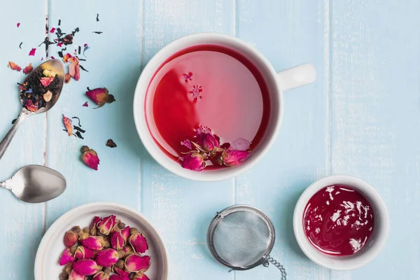 Chá de ervas e rosas secas na mesa de cor azul — Fotografia de Stock