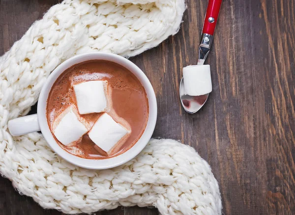 Cacao caliente con malvaviscos y bufanda de punto caliente en la mesa de madera, vista superior . — Foto de Stock