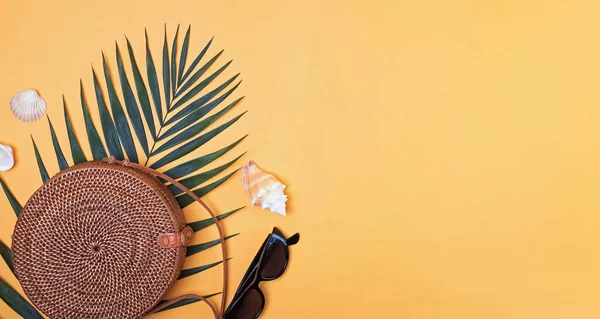 Stijlvolle ronde stro handtas met palmblad, zonnebrillen en seahells op de heldere gele achtergrond, — Stockfoto