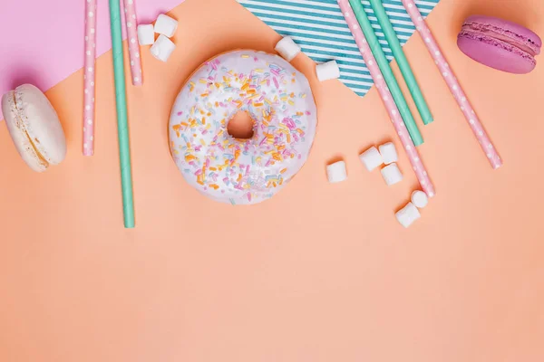 Donuts, macarons, marshmallows e palhas de papel sobre fundo pastel — Fotografia de Stock