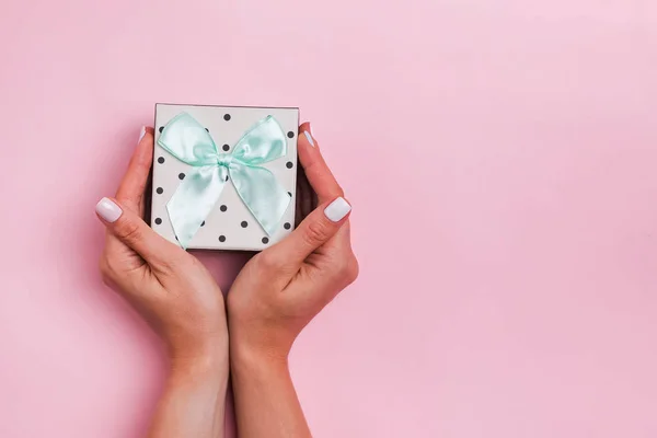 Dames handen houden een giftbox op roze achtergrond — Stockfoto