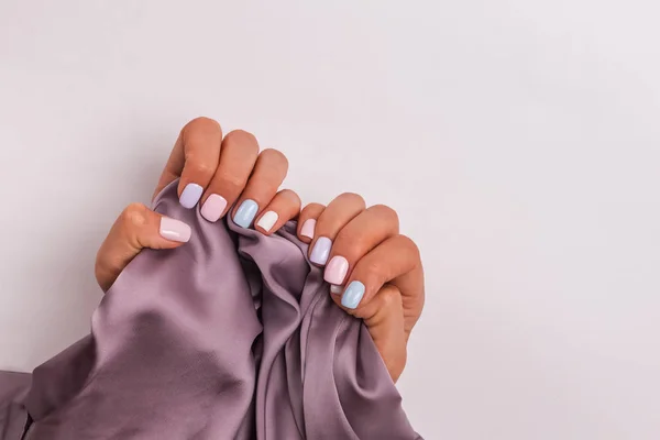 Mãos femininas fechar segurando um pano de seda e mostrando manicure bonito fresco — Fotografia de Stock