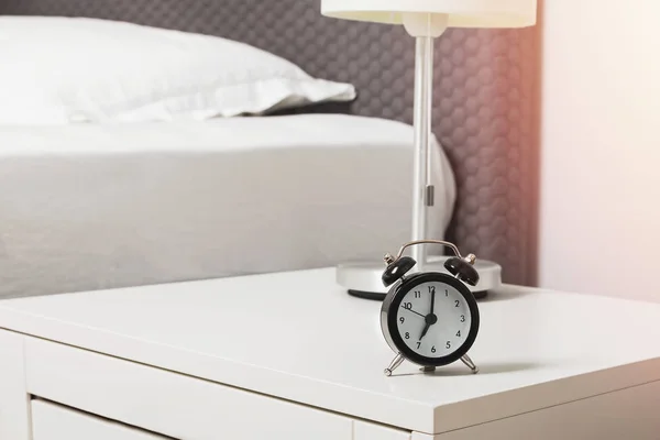 Wekker staat op de nachtkastje bij het bed — Stockfoto