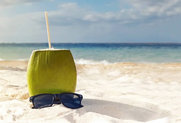 Napój kokosowy lub koktajl stojący na piasku i okulary przeciwsłoneczne na pięknej plaży. — Zdjęcie stockowe