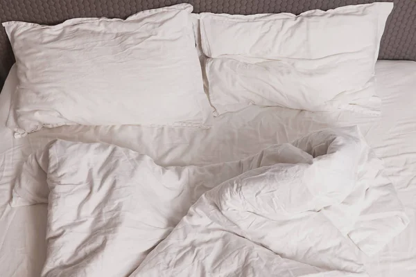 Несделанная кровать с белой простыней — стоковое фото