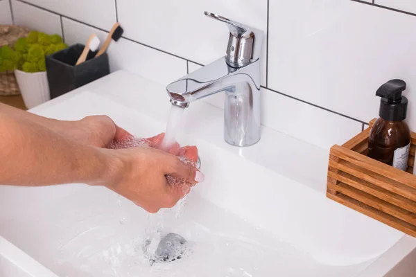 Женщина моет руки в современной ванной — стоковое фото