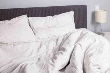 Beyaz yastık ve çarşaf ile dağınık yatak