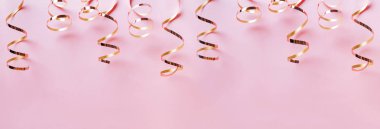 Pastel pembe arka plan üzerinde izole altın kıvırcık şeritler.