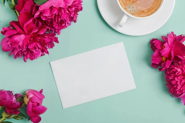 Kartu kosong mock-up di atas meja dengan peonies indah dan secangkir kopi — Stok Foto