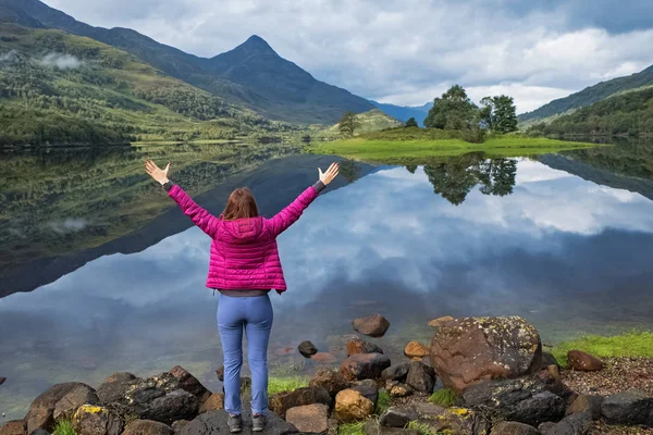 風光明媚な穏やかな湖の近くに立つ女性は、手を上げて. — ストック写真