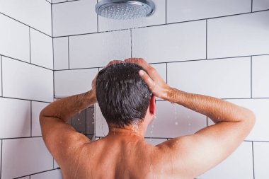 Beyaz kiremit ile modern banyoda duş alan genç adam