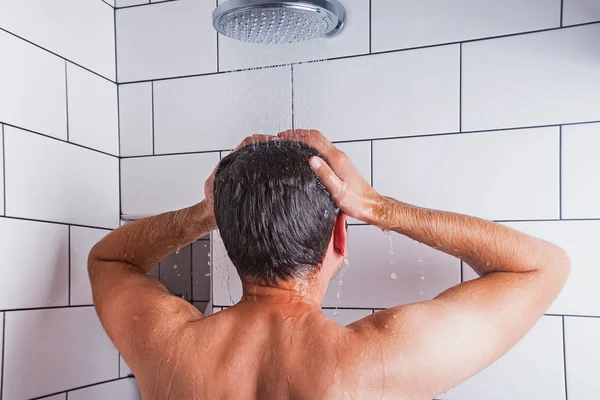 Joven tomando ducha en baño moderno con azulejo blanco — Foto de Stock