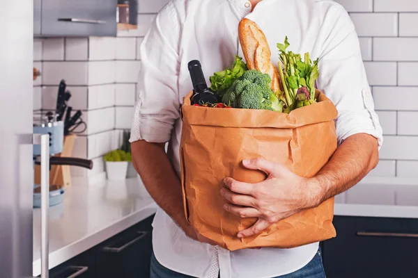 Man holding paper bag with different vegetable and other products