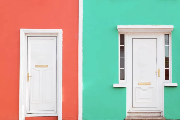 Facade colored in coral and mint colors with two white doors. — Stock Photo, Image