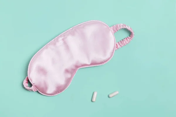 Sleeping mask and pills on pastel green background. — Stock Photo, Image