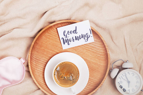Coffee, alarm clock and note with text Good Morning, top view