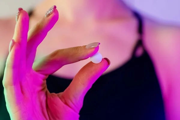 Womans mão close-up segurando pílula de drogas em luz de néon — Fotografia de Stock