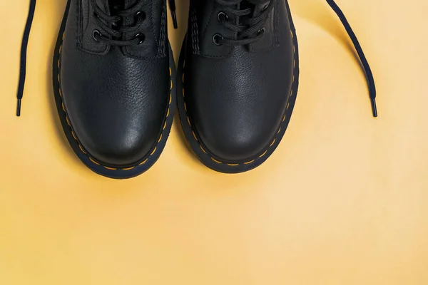 Klassische schwarze Lederstiefel auf gelbem Hintergrund — Stockfoto