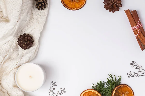 Creative winter frame with knitted sweater, pine cones, dry oranges and other objects